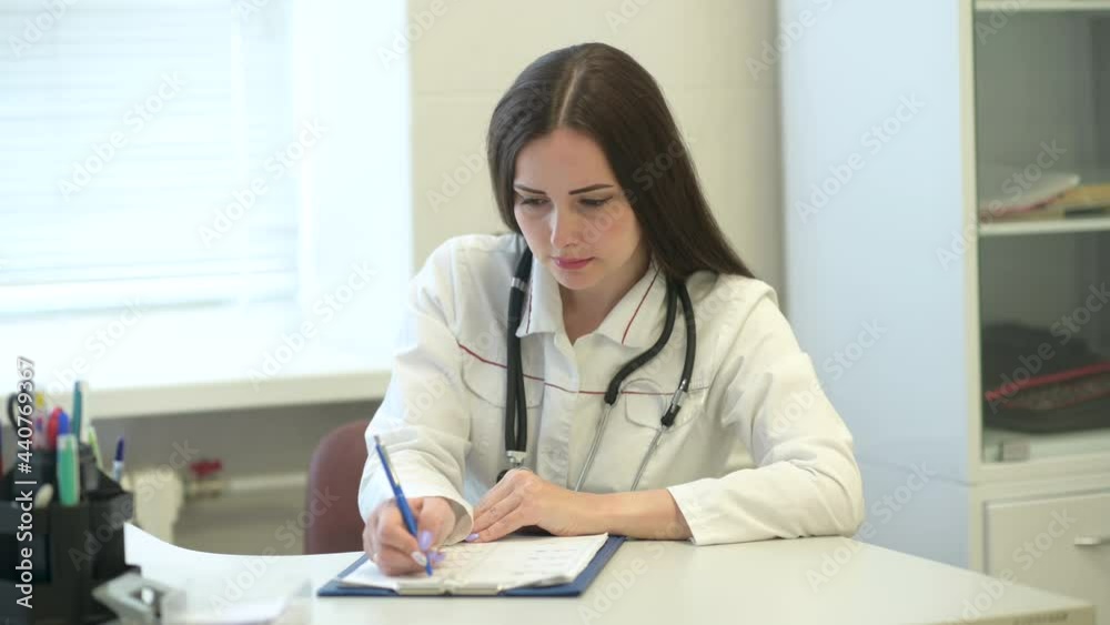 Female Doctor in medical Uniform sit at workplace desk In Hospital Office writing information in medical registration journal. Concept of health and safety life Female Doctor in medical Uniform sit at workplace desk In Hospital Office writing information in medical registration journal. Concept of health and safety life