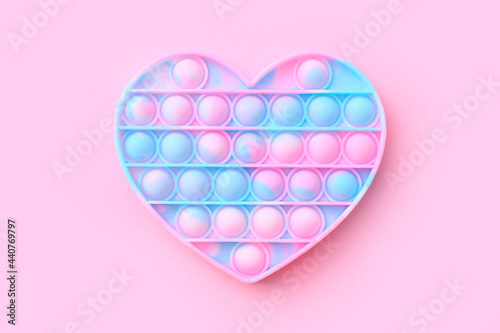 Colorful antistress sensory toy fidget push pop it in shape of heart on pink background, top view photo