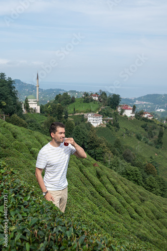 Young man degustating tea among tea bushes at Karadeniz region of Turkey photo