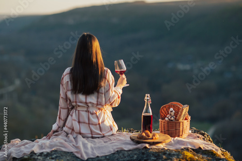 Photography Woman having a picnic on the mountain and drinking red wine.
