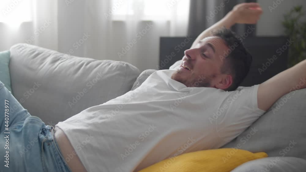 Happy relaxed young man rest lounge lean on couch enjoy peaceful mood, healthy lazy calm man dreaming breathing fresh air sit on comfortable sofa in living room on stress free cozy day at home Happy relaxed young man rest lounge lean on couch enjoy peaceful mood, healthy lazy calm man dreaming breathing fresh air sit on comfortable sofa in living room on stress free cozy day at home