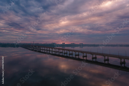 Aerial drone filmed sunset, burning sky over the city and water, beautiful sunset or sunrise. Panoramic view over the bridge with the sun © Denis Chubchenko