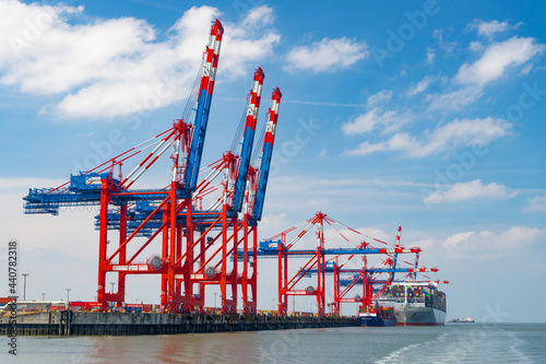 Gantry cranes unload a container ship on the Jade Weser in Wilhelmshaven, Lower Saxony - photo taken from the seaside