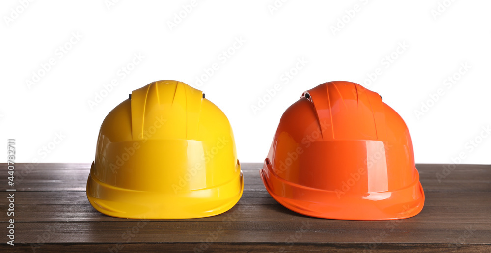 Fototapeta premium Different hard hats on wooden table against white background