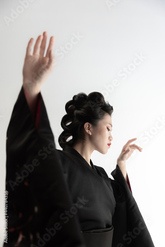 Portrait of young beautiful Japanese, woman in national attire kimono posing isolated over white studio background. photo