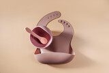 Brown silicone baby bib and and bowl. Serving baby. First baby accessories for dinner. Top view, flat lay