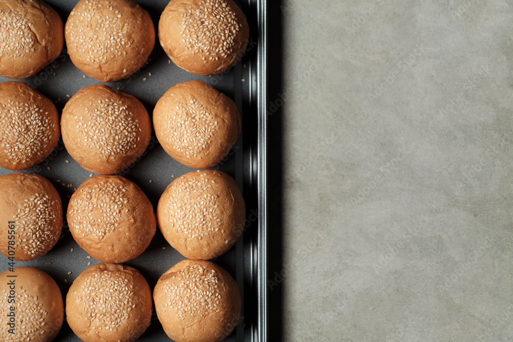 top view photograph shot with a half frame of many burger breads on the oven tray put on rusty kitchen table with empty copy space top view photograph shot with a half frame of many burger breads on the oven tray put on rusty kitchen table with empty copy space