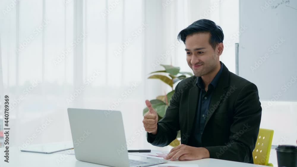Smiling Asian businessman working on laptop computer at home office to make video calls on your laptop Smiling Asian businessman working on laptop computer at home office to make video calls on your laptop