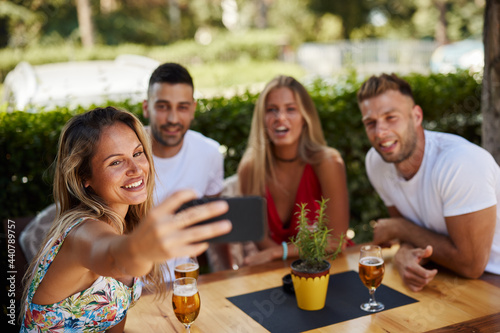 Group of young people having fun in a sumemer bar and taking selfie