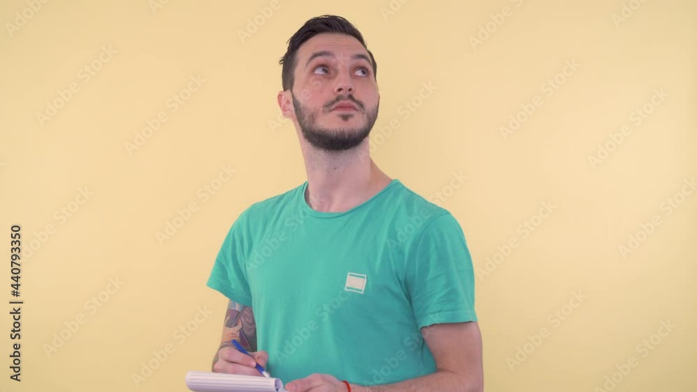 Young man with pen and notebook looking upside and taking notes Young man with pen and notebook looking upside and taking notes