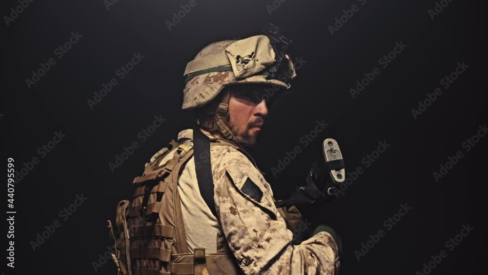 Soldier turns to look at viewer then aims rifle to provide cover fire, in studio isolated on black background. Soldier turns to look at viewer then aims rifle to provide cover fire, in studio isolated on black background.
