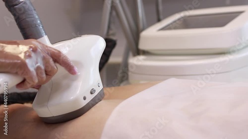 Hardware anti-cellulite massage. RF lifting procedure. The beautician guides the device along the client's leg. Ultrasound cavitation body contouring treatment. Anti-fat therapy.