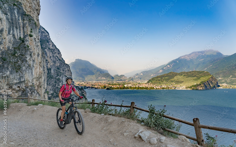 nice and active senior woman riding her electric mountainbike on the famous Tremalzo downhill from Tremalzo Pass to Riva del Garda at Garda lake, Trentino, Izaly nice and active senior woman riding her electric mountainbike on the famous Tremalzo downhill from Tremalzo Pass to Riva del Garda at Garda lake, Trentino, Izaly