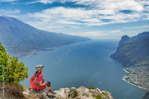 nice senior woman with elctric mountain bike resting at Punta Larici and enjoying the awesome view over Garda Lake between Riva del Garda and Torbole © Uwe