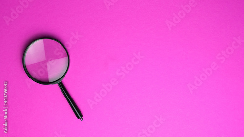 Magnifying glass on a hot pink background. Top view. Copy space for text.