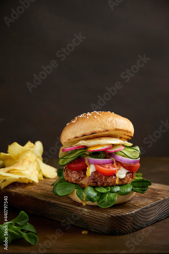 fresh tasty burger isolated on dark background with chips. Copy space concept.