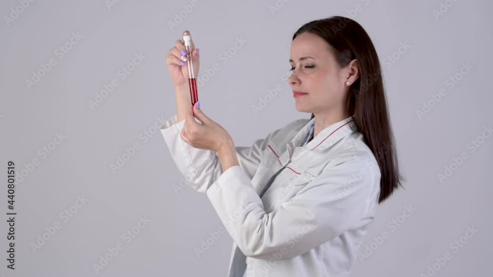Female Doctor in medical Uniform looks at test tube with blood isolated on white background. Health and medical concepts. Female Doctor in medical Uniform looks at test tube with blood isolated on white background. Health and medical concepts.