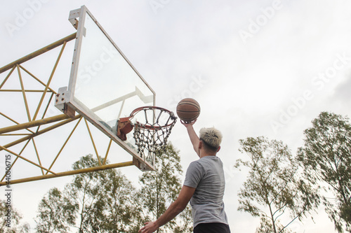 Young man basketing a ball from the air, in an abandoned court.
