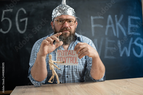 a conspiracy theorist in a foil hat controls a wooden man and the inscription is total control. conspiracy theory and conspiracy theory. Fake news. Manipulation and puppet.