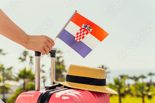 Fototapeta Naklejka Na Ścianę i Meble -  Woman with pink suitcase and Croatia flag standing on passengers ladder and getting out of airplane opposite sea coastline with palm trees.