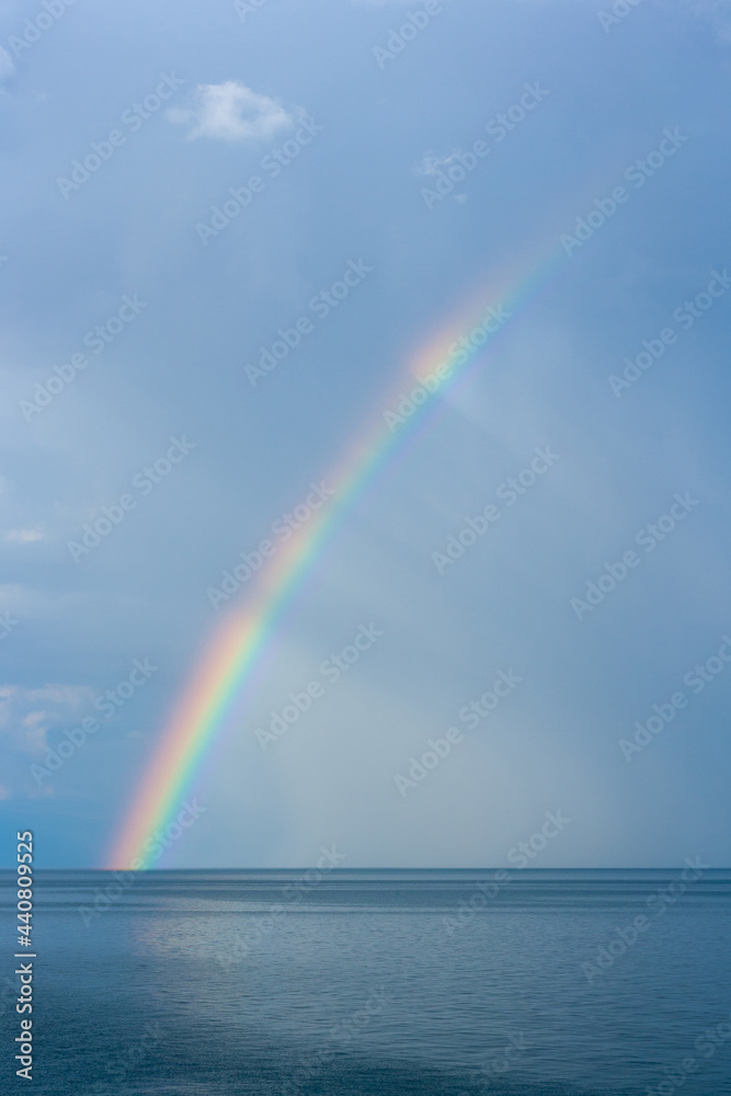 Rainbow over Lake Baikal against the background of rain clouds. Vertical image. Rainbow over Lake Baikal against the background of rain clouds. Vertical image.
