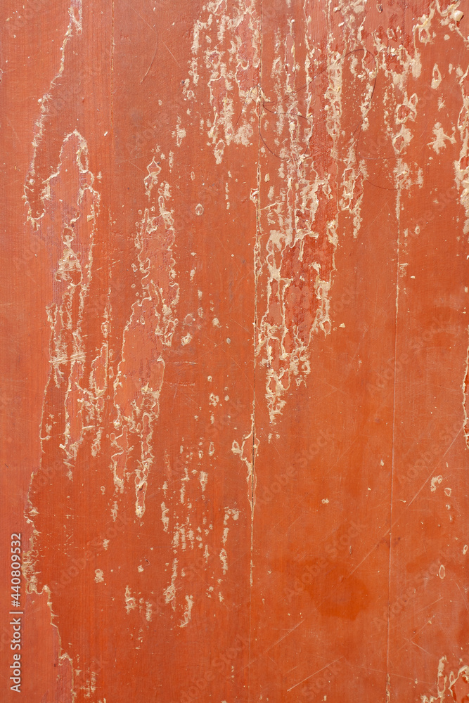 Fototapeta premium Old wooden panels with peeling red surface with scratches. Vertical image.