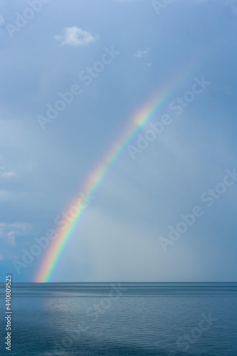 Rainbow over Lake Baikal against the background of rain clouds. Vertical image.