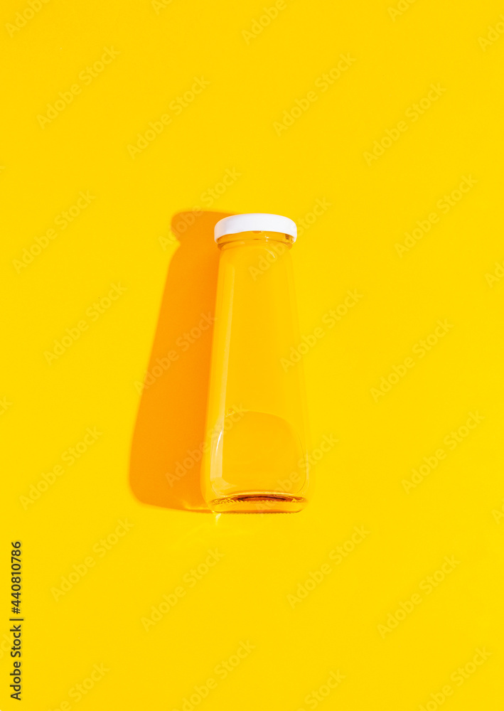A bottle of orange, carrot juice on a yellow background. A bottle of orange, carrot juice on a yellow background.