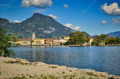 Riva del Garda, Italy- garda lake with Monte Brione, peaks, town, plants, beach, shore, blue sky photo