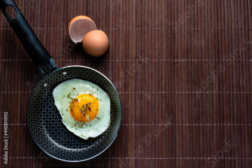 Frying pan with fried egg on a bamboo table