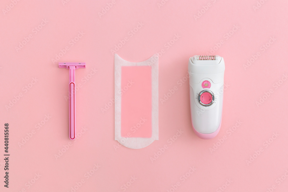 Razor, wax strips and modern electric epilator on pink background Razor, wax strips and modern electric epilator on pink background