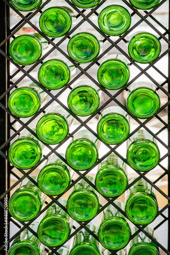 Wall with green glass bottles on the shelf. Interior decoration