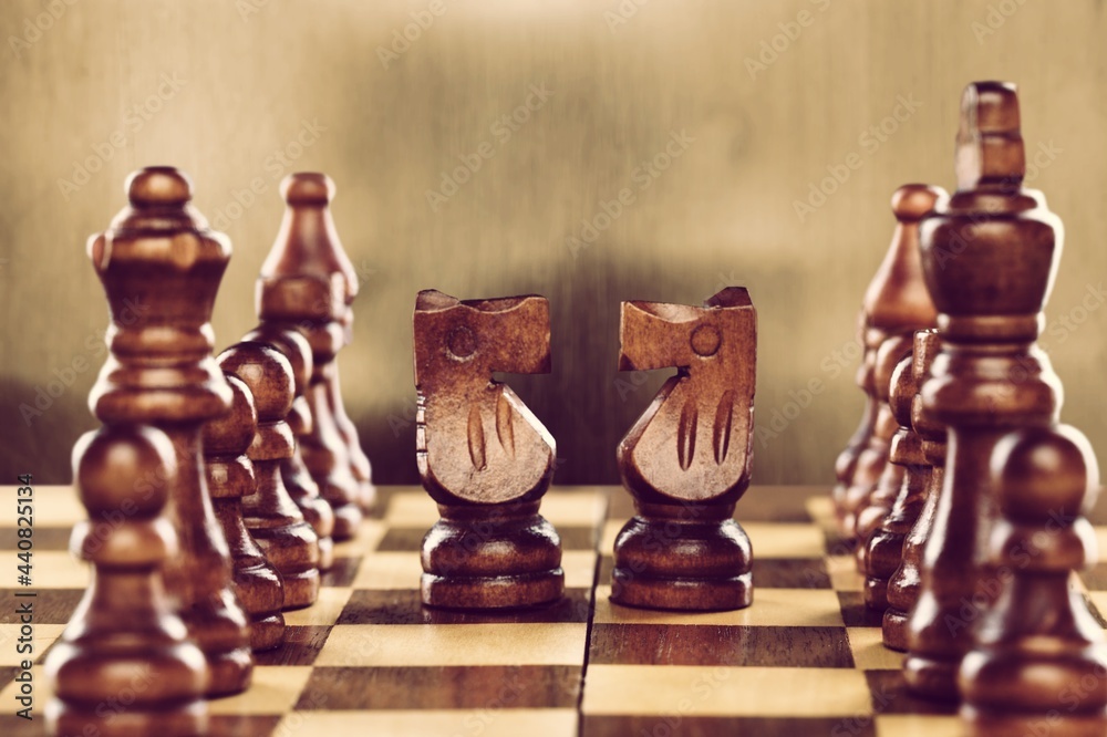 Wooden chess pieces facing each other on a vintage chessboard. Rivalry ...