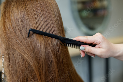 A woman in a barber shop combs her long hair