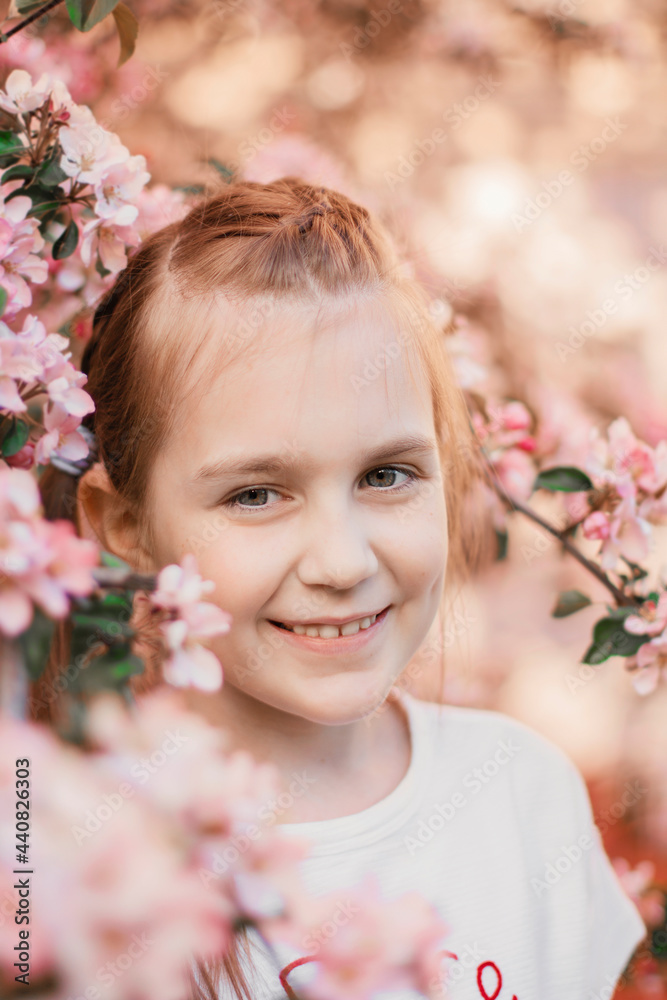 Fototapeta premium Pretty teen girl with nice smile looking at camera. Apple tree blossom.