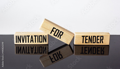 Wooden blocks with the text INVITATION FOR TENDER on a black and white background.