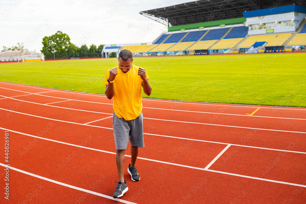 Fototapeta premium Joyful young african american male in sportswear triumphant smiling celebrating goal, match win screaming with joy on the stadium background, happy excited black winner celebrating success victory