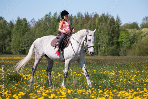 Little girl in pink rides a white horse