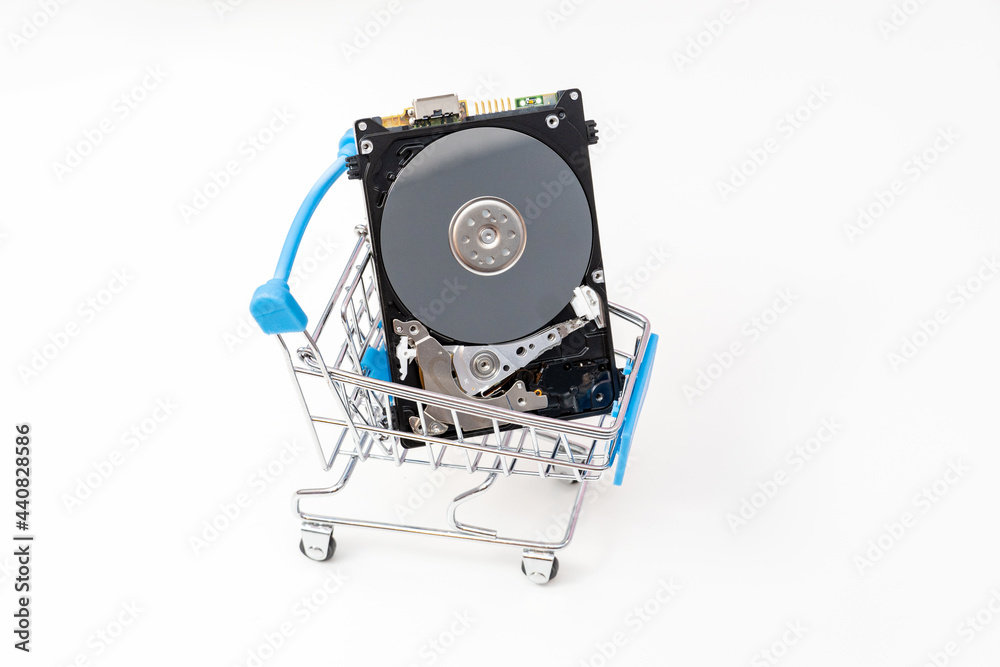 Fototapeta premium Open hard disk drive in shopping cart. Information, data storage infrastructure cost concept.