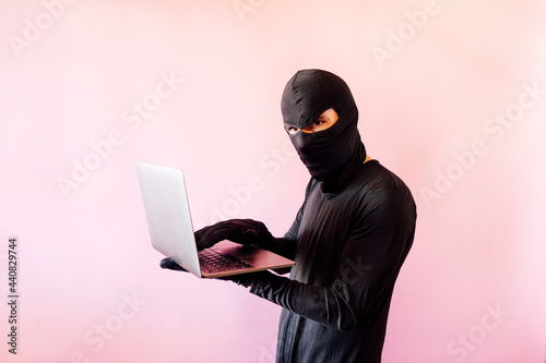 Thief man dressed in black with laptop