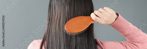 Brunette woman combs her hair with comb