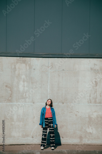 Hipster girl wearing sunglasses standing in front of the urban wall and posing