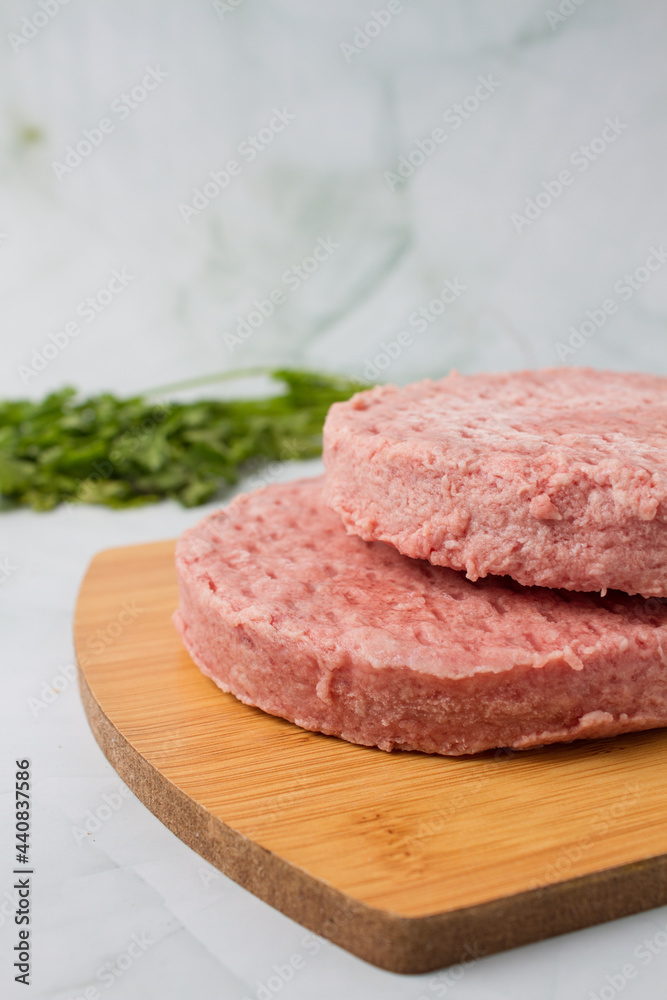 raw burger meat with herbs over a wood table, green background