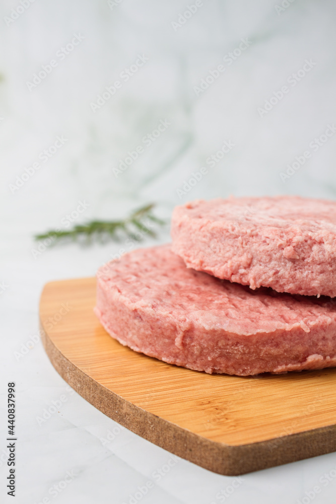 raw burger meat with herbs over a wood table, green background raw burger meat with herbs over a wood table, green background