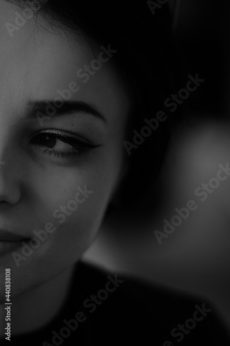 A happy young girl in a black leather jacket and short hair is sitting at a table. Black and white portrait of a smiling woman  © Yevhen
