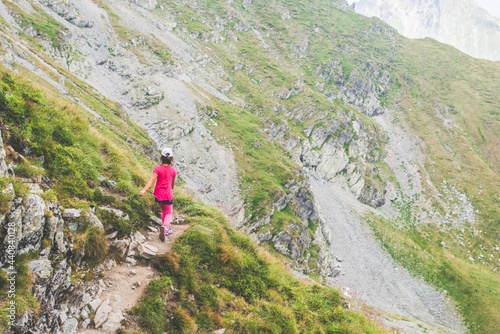 Little girl walking alone on a path on top of a mountain