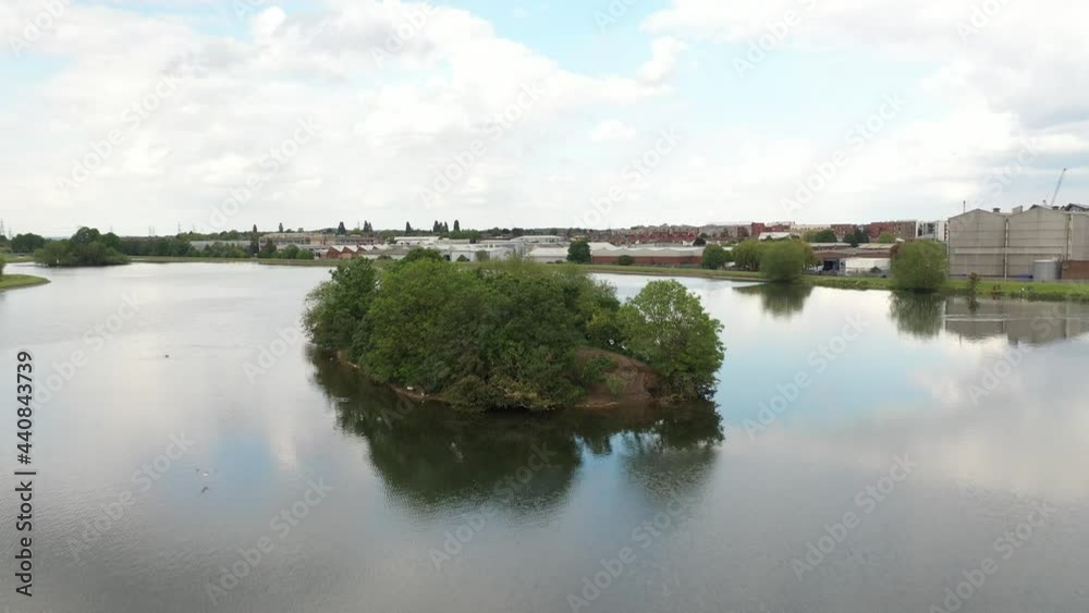 Backwards flying over island and descending close to water surface. Rippled water reflecting grey sky Backwards flying over island and descending close to water surface. Rippled water reflecting grey sky