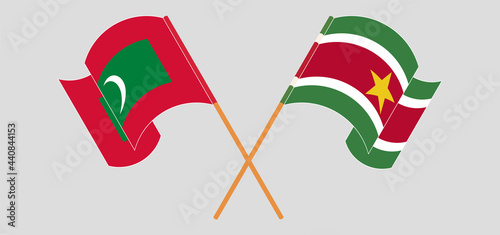 Crossed and waving flags of Maldives and Suriname
