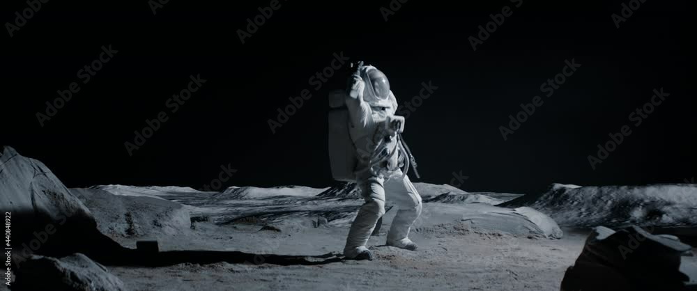 Male astronaut performing moonwalk dance move on a Moon surface. Shot with 2x anamorphic lens