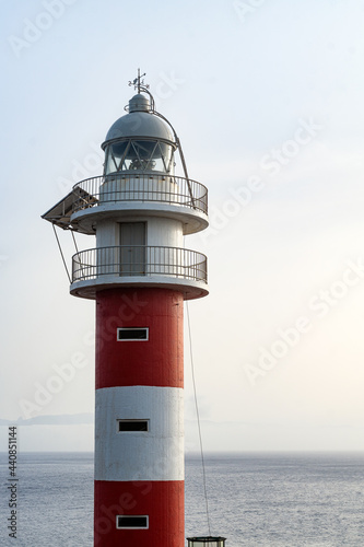 Lighthouse in sunset time on the ocean and blue sky background